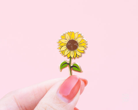 Cute yellow sunflower enamel pin featuring a woman's body in the center of the sunflower