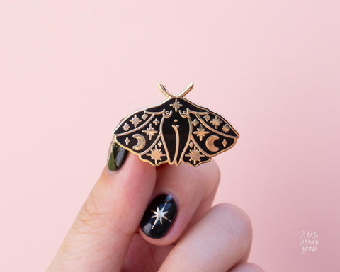 Black and gold enamel pin featuring original feminist artwork of a moth lady. Stars, moon, celestial motifs decorate the moth girl's wings.