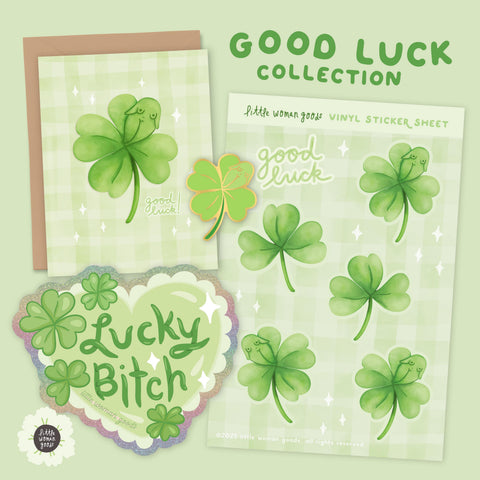 A Good Luck Collection set that features four items. A glittery, green heart sticker with the text "lucky bitch”. The sticker sheet has the text “good luck” and five different green clover designs. Three of the stickers features a hidden female body. The greeting card features a four leaf clover with a hidden female body in the design with the text “good luck”. Finally, the pin is a green, four leaf clover with a hidden female body in the design.